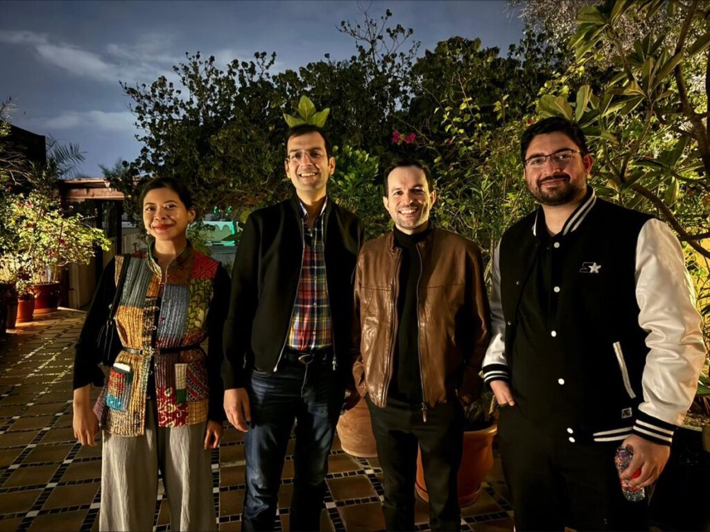 Four attendees standing on a planted, tiled terrace at dusk during the Oxford Society in UAE winter networking evening.