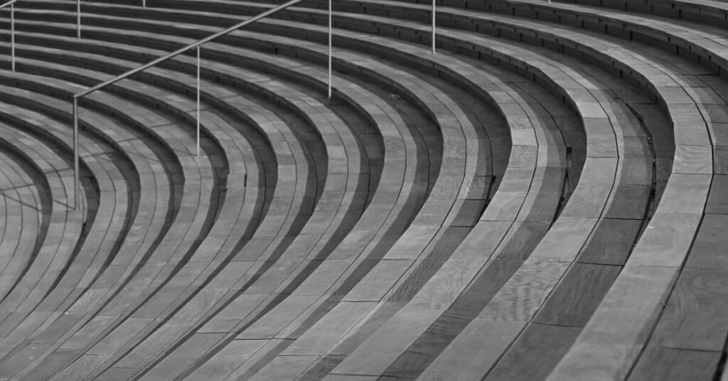 Curved concrete steps with metal railings in greyscale